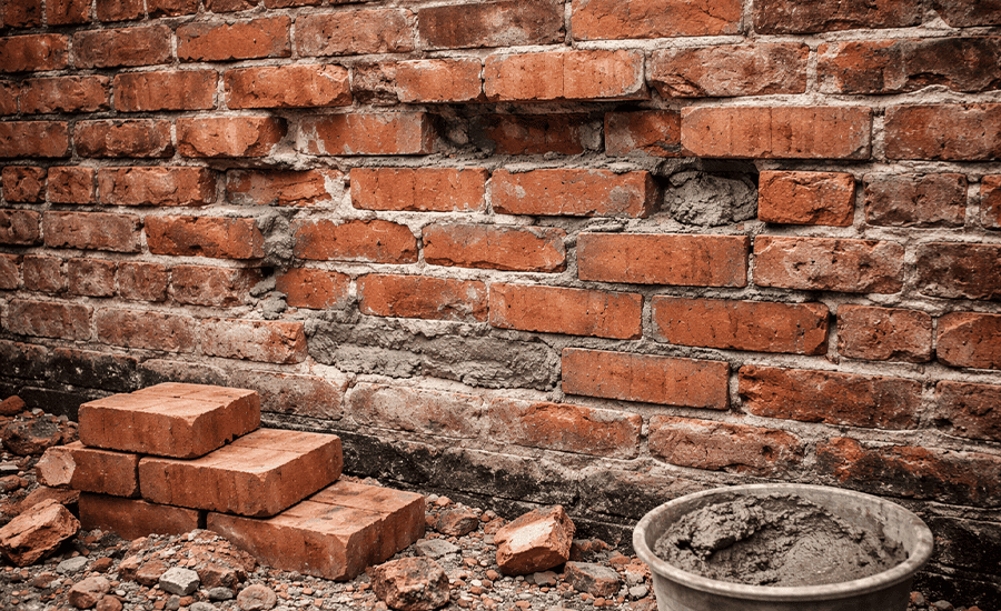 Damaged brick wall being repaired with fresh mortar and replacement bricks