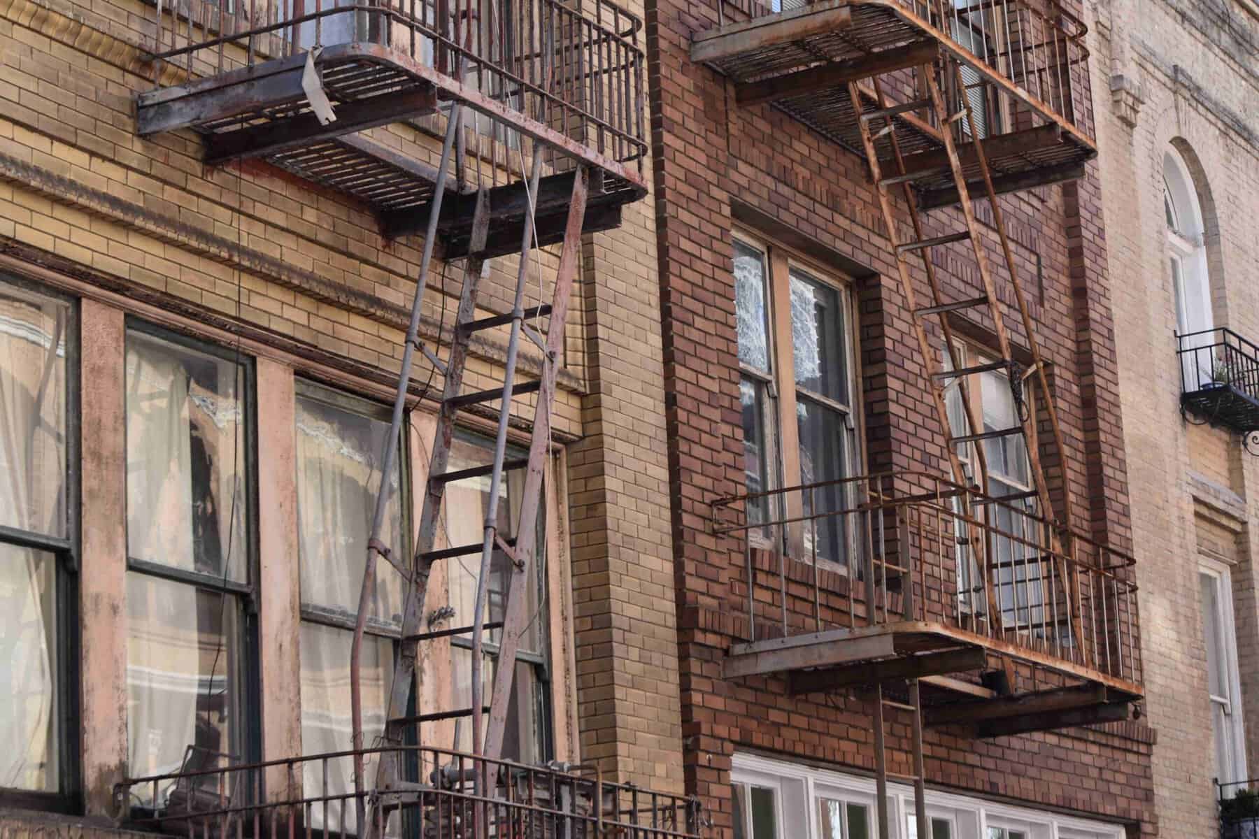 rusted fire escape in NYC building showing corrosion and structural damage signs rusted fire escape in NYC building showing corrosion and structural damage signs