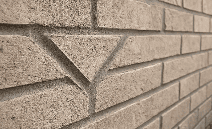 Mason performing V-pointing on brick wall with trowel for decorative finish