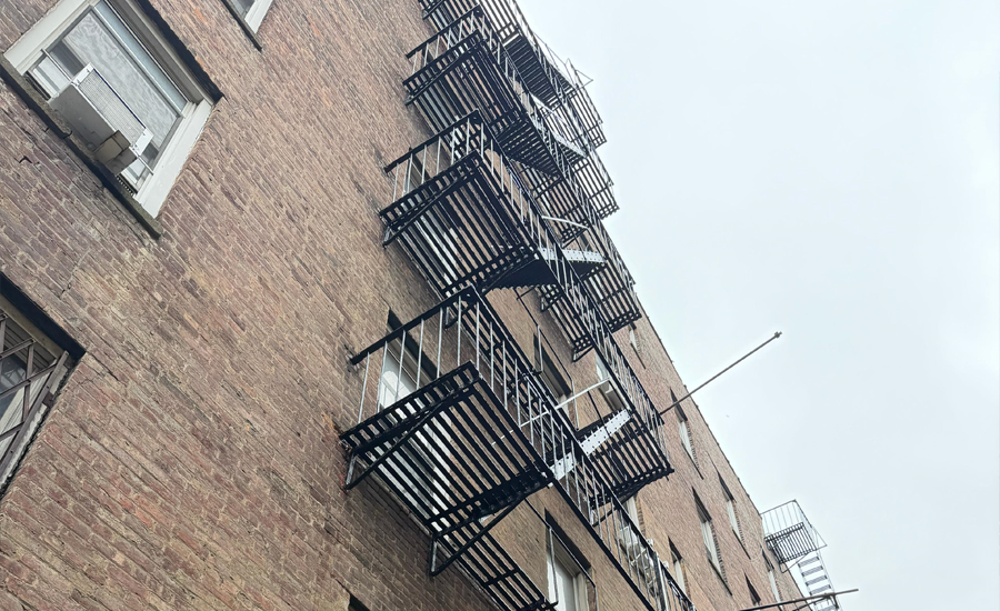External fire escape staircase attached to a historic NYC building, showing classic iron structure and safety design under city fire code compliance.