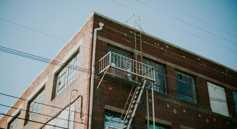 Metal fire escape on NYC apartment building showing rust and corrosion on stairs and railing