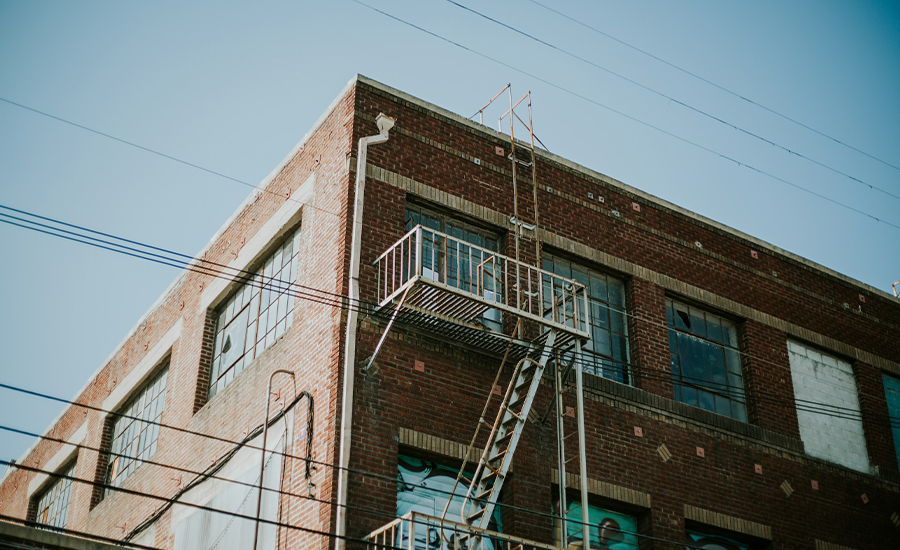 Metal fire escape on NYC apartment building showing rust and corrosion on stairs and railing