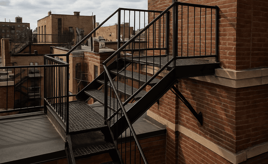 Rooftop fire escape system on NYC building showing secure metal stairway and access ladders for emergency evacuation
