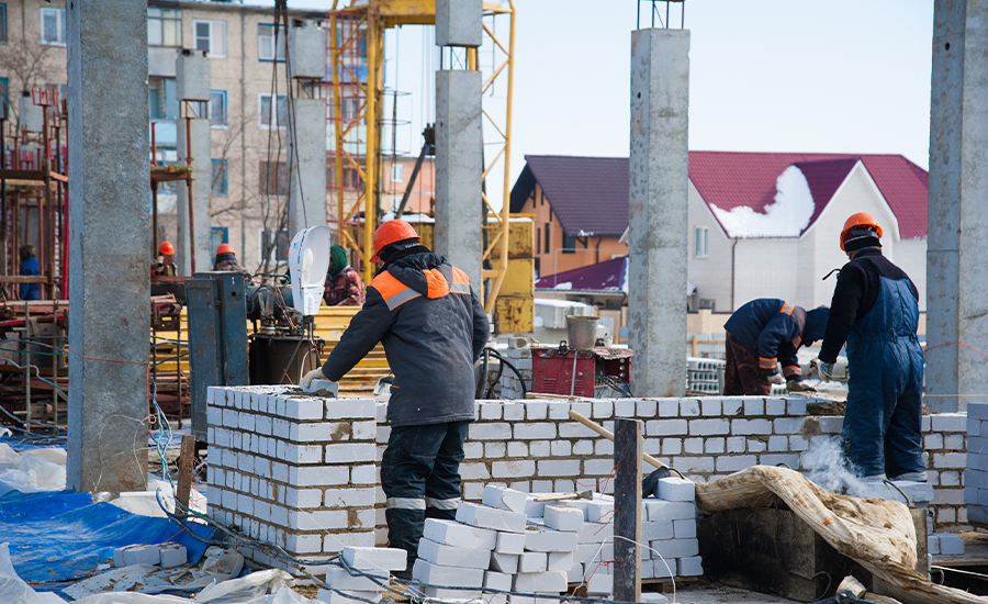 Masonry contractor working on brick and mortar repairs during winter using insulated covers and temperature-controlled tools in NYC.
