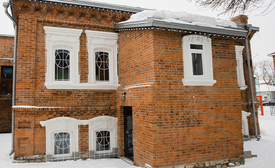 Brickwork repairs being done in cold weather with insulated tarps and winter-grade mortar to prevent freezing and weak joints.