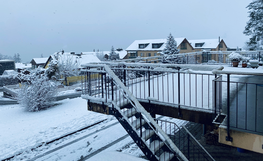 Snow and ice buildup on an old NYC fire escape causing rust, cracks, and unsafe slippery steps.
