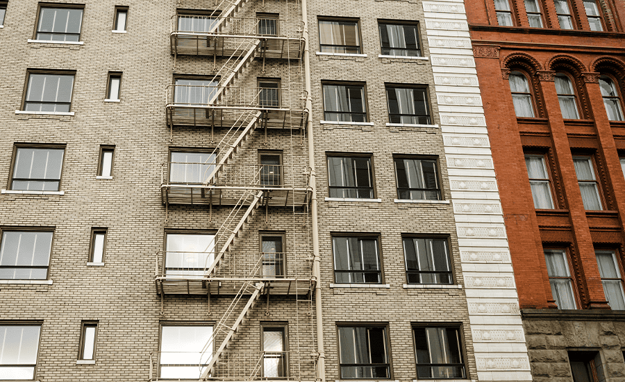 Fire escape covered in light snow on a New York City building during winter, showing safe and well-maintained metal stairs and railings.