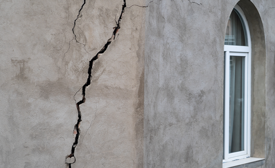 Stucco cracks during cold weather on NYC building wall showing winter damage and moisture effects.