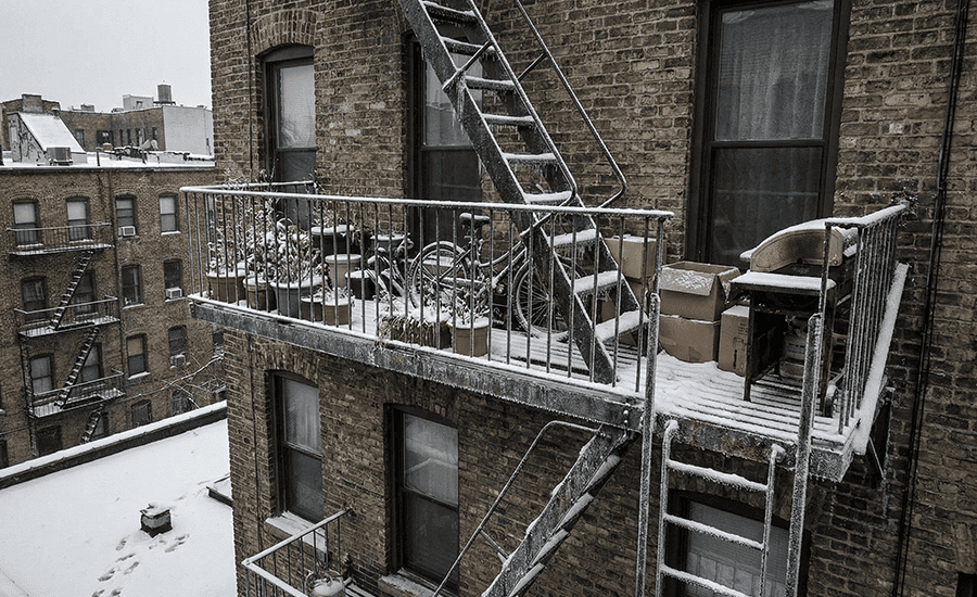 NYC fire escape covered with snow and ice during winter, showing slippery steps and safety hazards homeowners must avoid