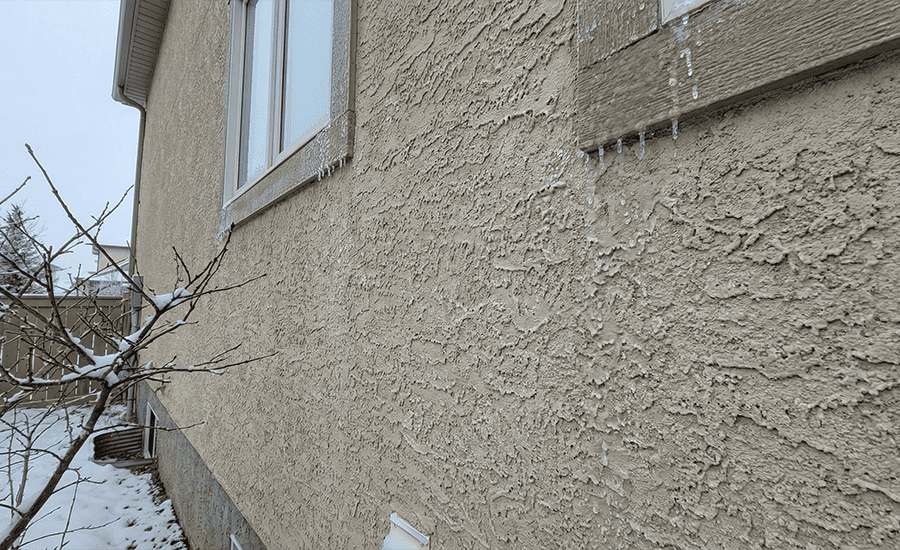 Stucco exterior wall showing winter freeze thaw moisture near window frame