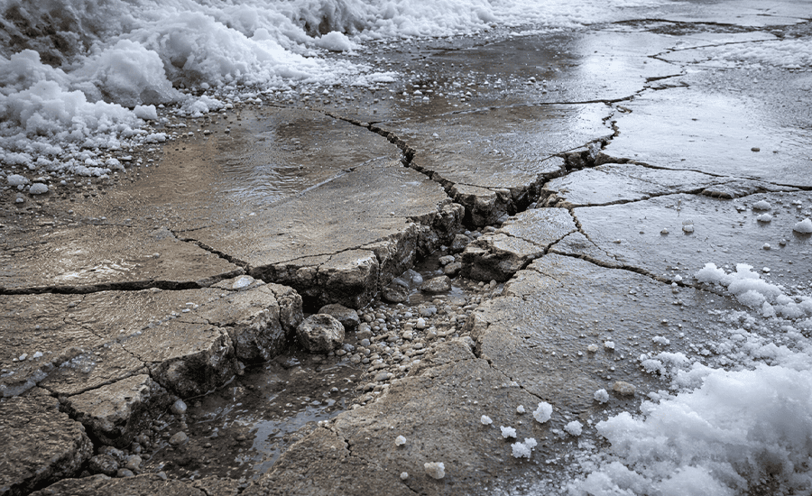 Cracked concrete floor damaged by frost and snow during winter conditions