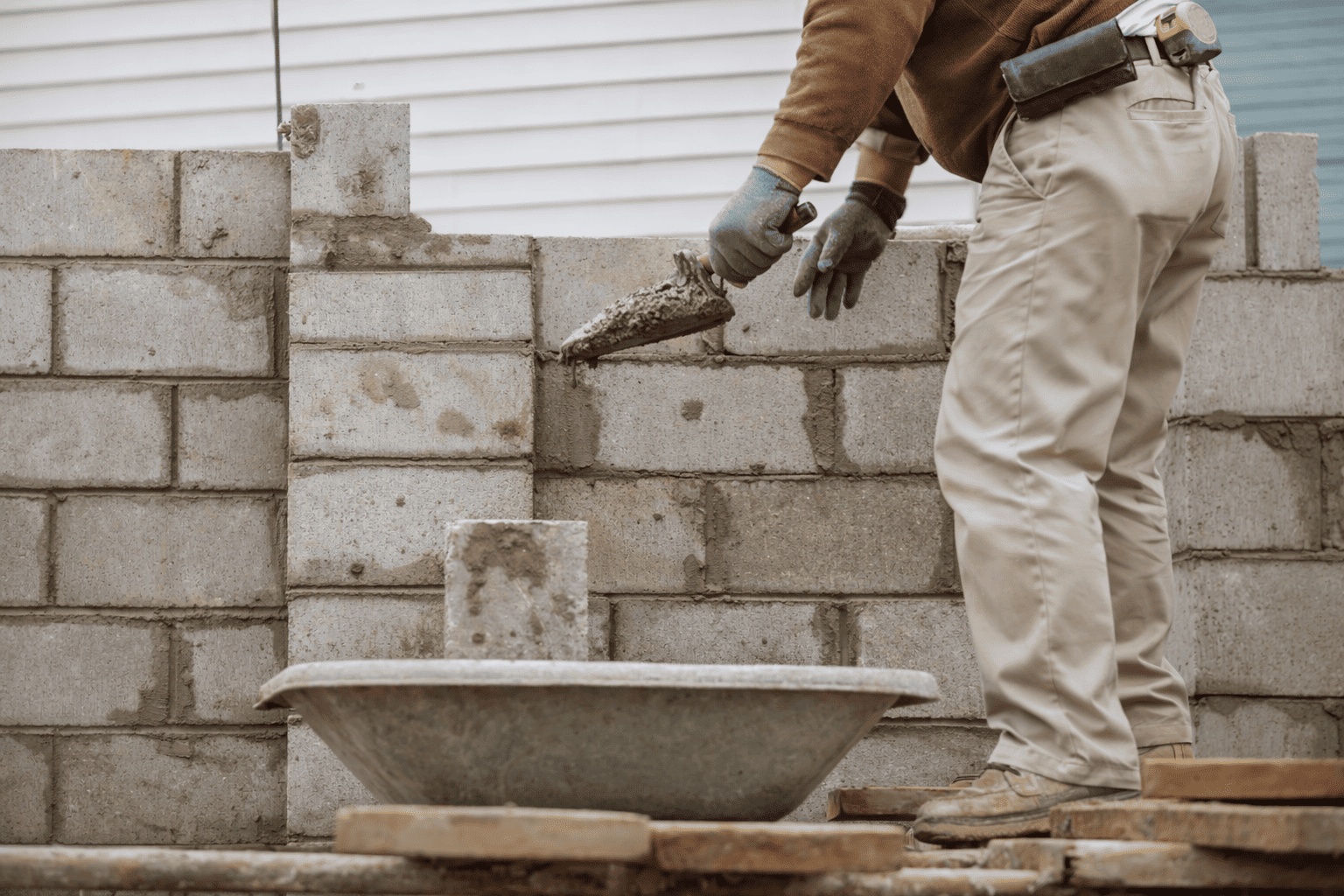 masonry contractor applying mortar while building a concrete block wall on a construction site