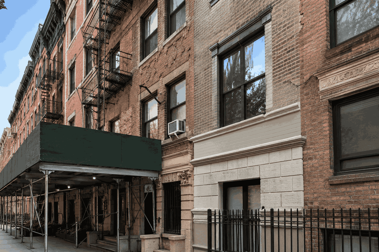 Early façade repair work on an NYC brick building with sidewalk scaffolding and visible exterior masonry details Early façade repair work on an NYC brick building with sidewalk scaffolding and visible exterior masonry details