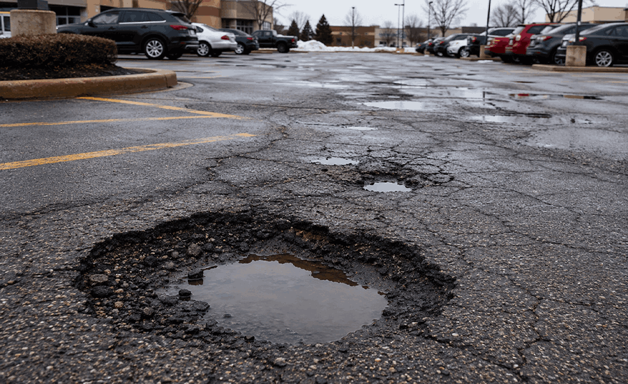 Damaged NYC parking lot with cracks and potholes caused by water infiltration, traffic pressure, and pavement wear
